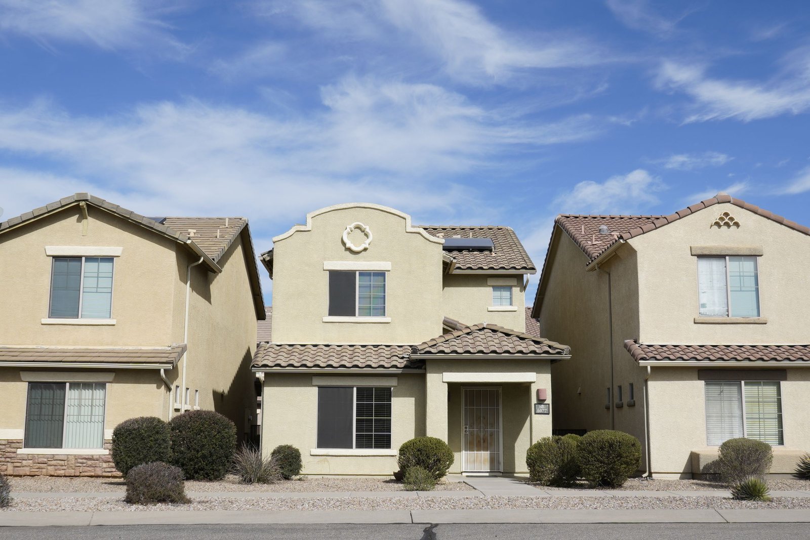 Beige stucco single-family home with a clay tile roof and desert landscaping